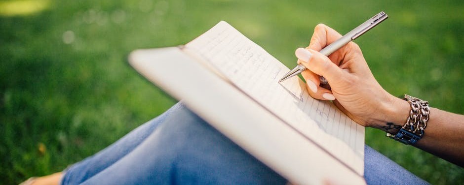 Image of writer writing in a journal