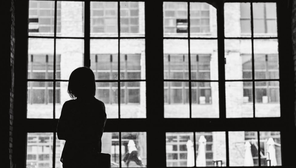 Image of woman looking out the window for her apartment